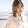 woman near beach smiling and wearing reed wig